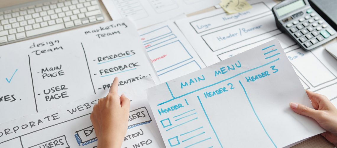 UX designer analyzing layouts in front of him when creating layout of website interface of new company